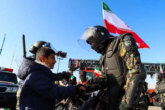 A member of Iran's security forces shakes hand with a young boy, in a state-sponsored event in central city of Yazd, January 27, 2026