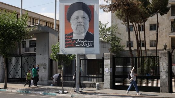 A woman walking past a banner of Iranian President Ebrahim Raisi in Tehran, May 2024