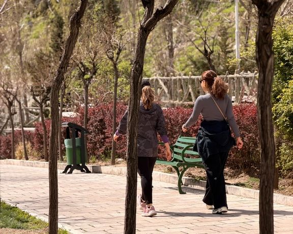Two young women stroll in a Tehran park a day after the ceasefire between Iran and the United States