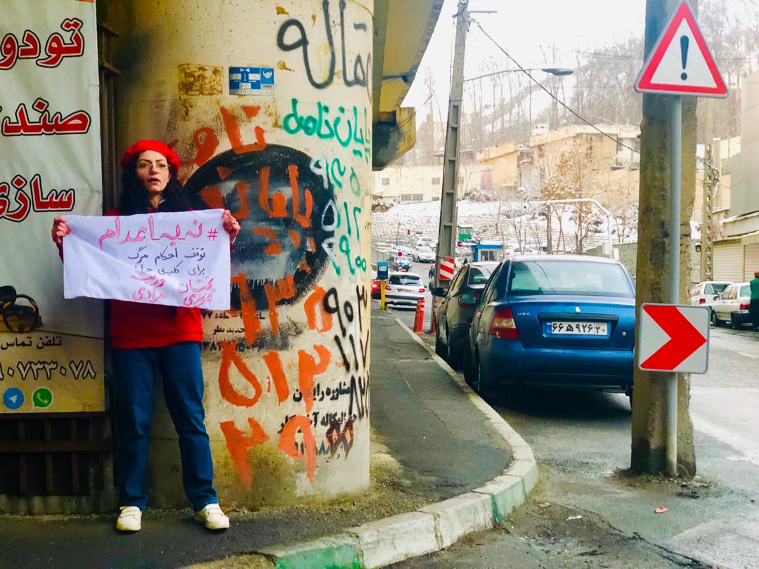 مریم یحیوی پس از آزادی پارچه‌نوشته «نه به اعدام» را مقابل زندان اوین در دست گرفت