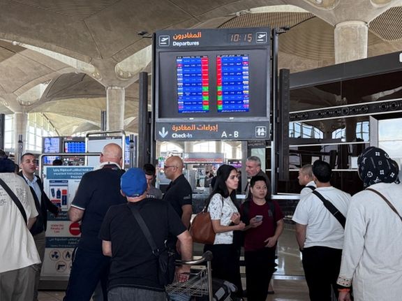 People stand in front of a flight information display screen showing information about delayed and cancelled flights, at Queen Alia International Airport in Amman, Jordan June 13, 2025.