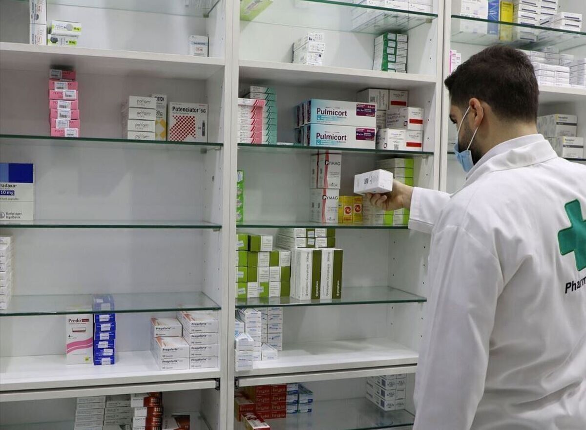 A pharmacist arranges medicine boxes on shelves at a pharmacy in Iran amid ongoing shortages and rising drug prices.