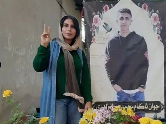 Mahsa Yazdani beside a photo of her son Mohammad Javad Zahedi, one of the victims of Women, Life, Freedom movement