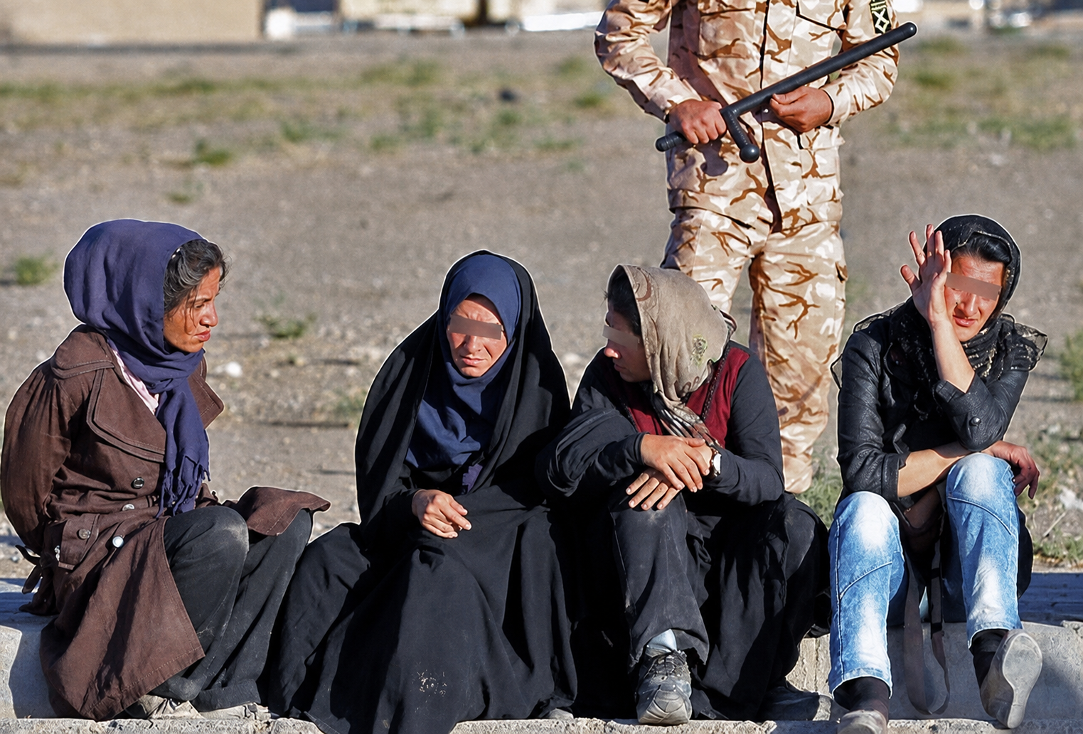 Four women with drug addiction sit beside an armed officer in an undated image from Iran.