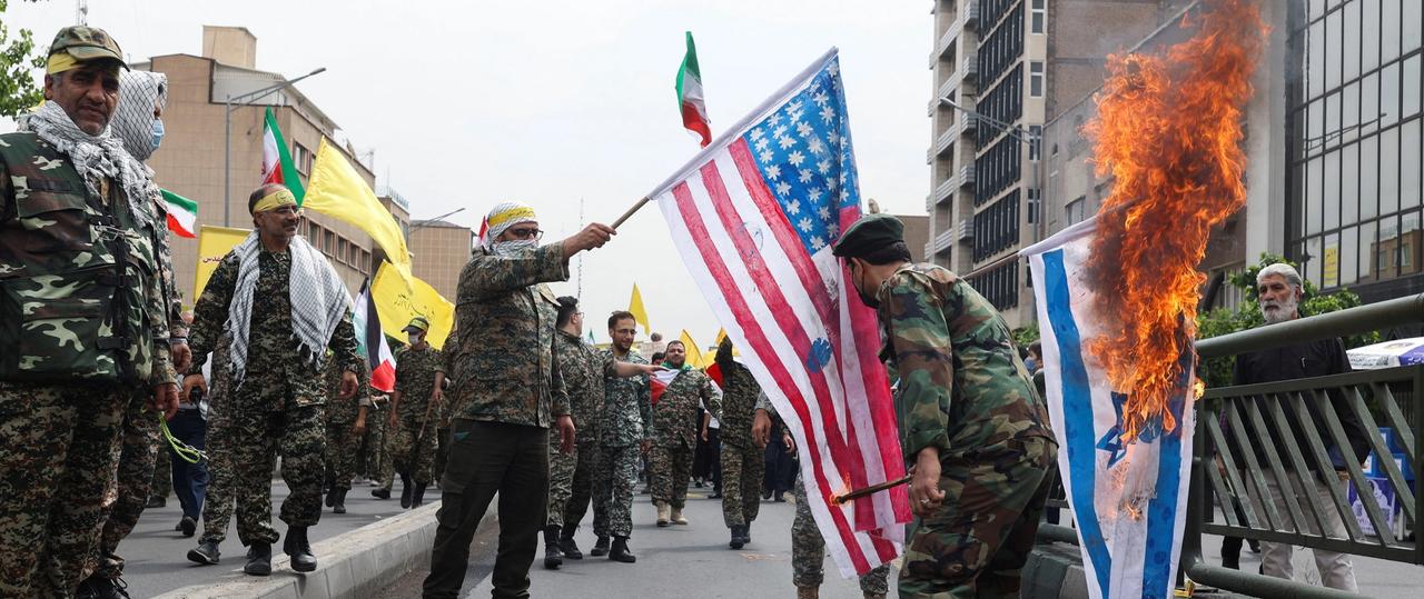 Men in military uniforms setting fire to Israeli and US flags during Quds day rallies in Tehran on April 29, 2022 