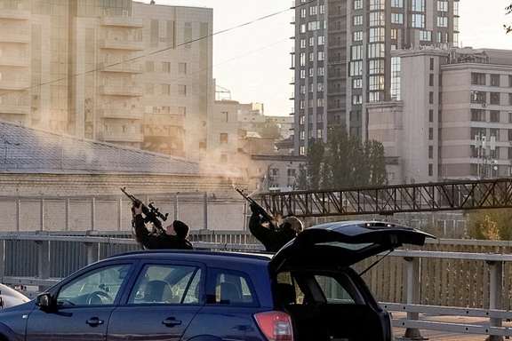 Ukrainian policemen use their assault rifles to fire at drones over Kyiv.