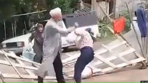 A screen grab from video showing a cleric beating an elderly woman in Iran.