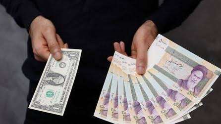 A currency dealer poses for a photo with a U.S one dollar bill and the amount being given when converting it into Iranian rials in an exchange shop in Tehran, Iran December 25, 2022.