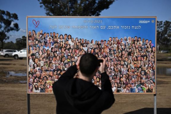 A person takes a picture of photos of the people who were killed and kidnapped during the October 7 attack by Hamas gunmen from Gaza, at the site of the Nova festival, amid the ongoing conflict between Israel and the Palestinian Islamist group Hamas, in Reim, southern Israel, February 1, 2024.