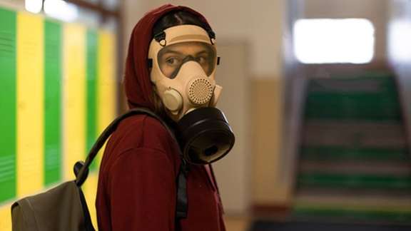 A schoolgirl breathing through a mask (file photo)
