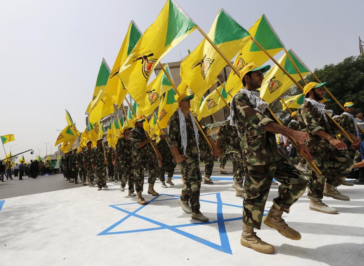 Iraqi Shiite Muslim men from the Iranian-backed militia Kataib Hezbollah hold the party's flags as they walk along a street painted in the colours of the Israeli flag during a parade in Baghdad in this July 25, 2014. 