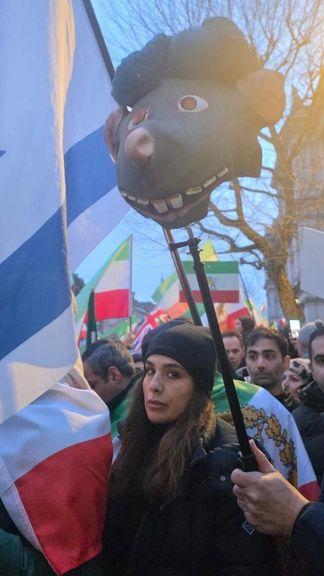Protesters hold a rat’s head wearing a turban during a rally in support of protests in Iran