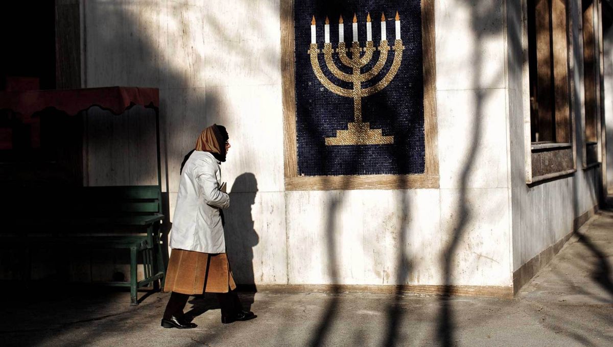 An Iranian woman walking past a Hanukkah menorah symbol   (file photo)