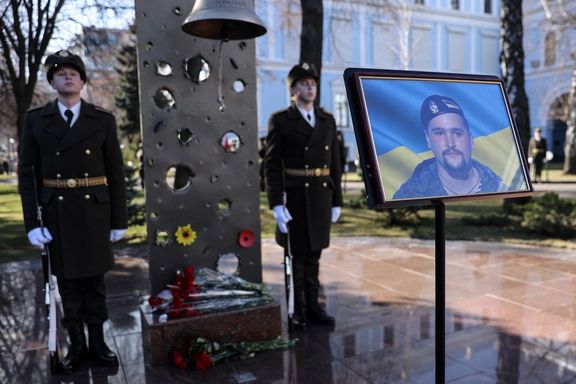 Ukrainian soldiers stand behind the portrait of a serviceman killed on February 19 in a shelling of Ukrainian positions. February 22, 2022