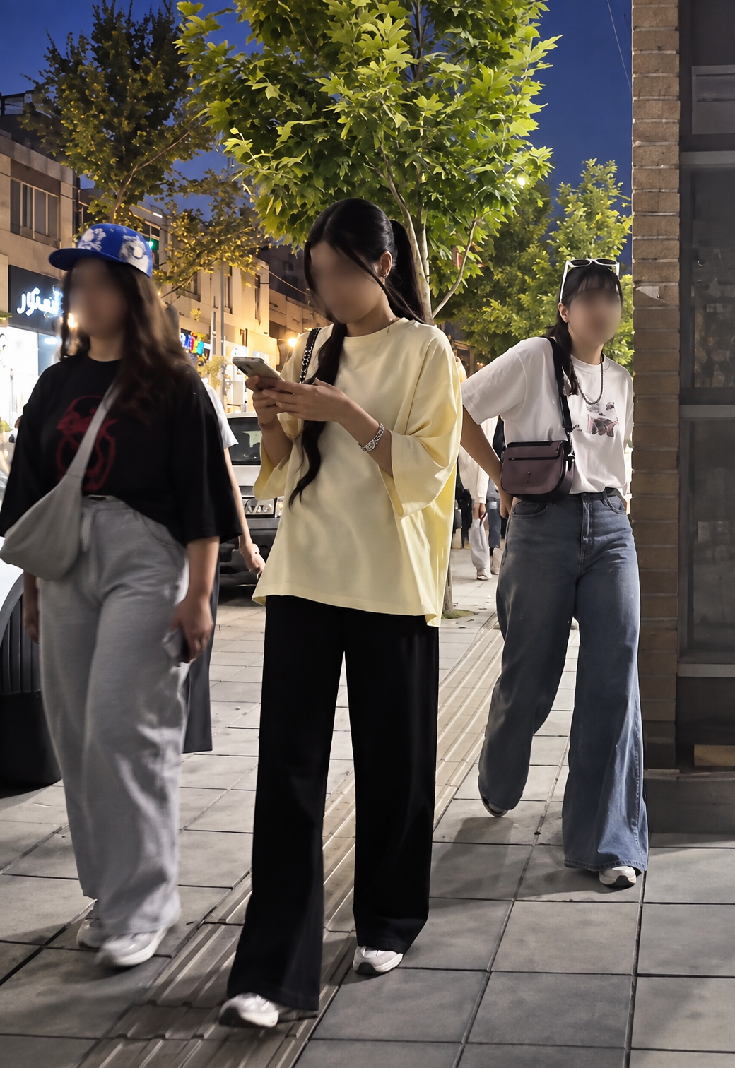 Women without mandatory hijab walk along a street in Iran.