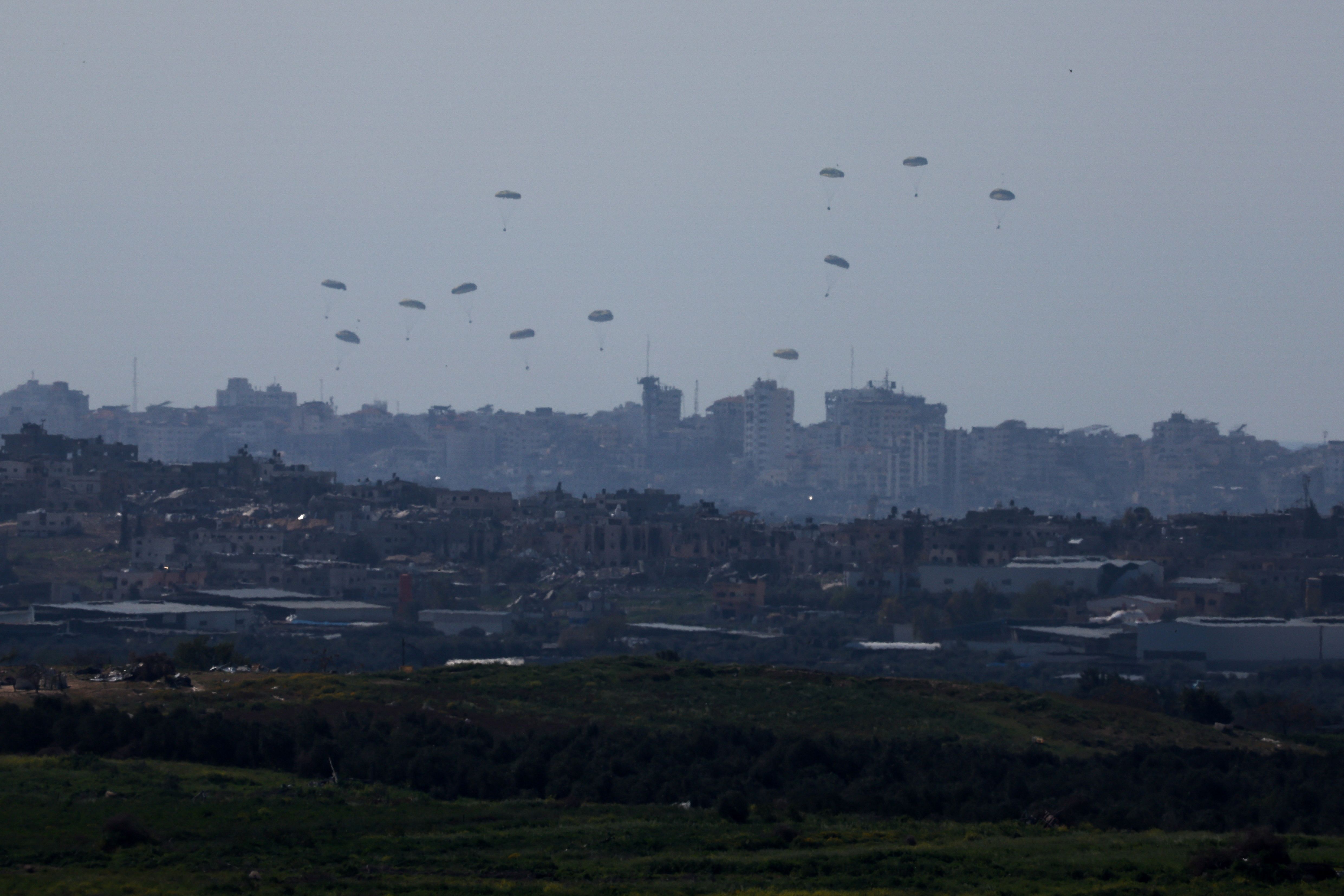 Packages fall towards northern Gaza, after being dropped from a military aircraft, amid the ongoing conflict between Israel and the Palestinian group Hamas, as seen from Israel's border with Gaza, in southern Israel, March 11, 2024.