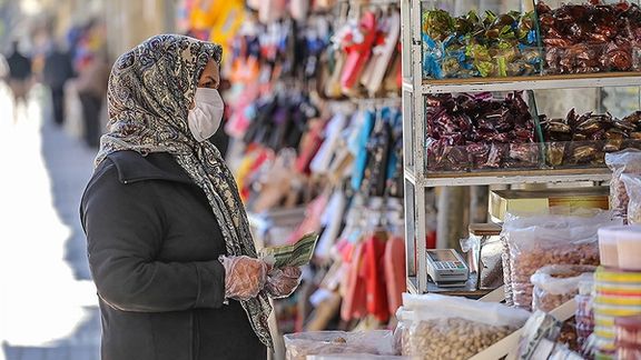 A woman shopping in Tehran with Iranian currency in hand