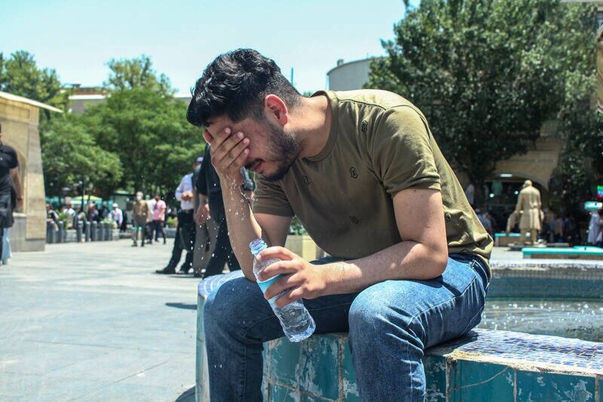 A young man cools off by a fountain during a heatwave in Iran, using bottled water to combat the temperatures (Undated)
