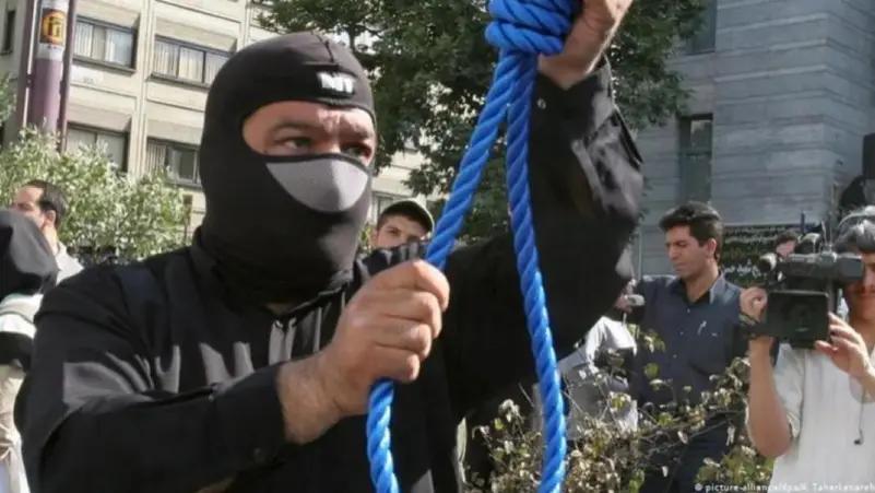 A masked executioner prepares a noose for a public hanging in Iran (Undated)