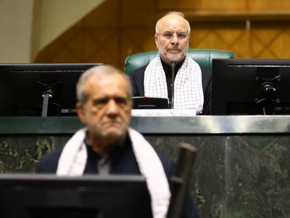 Speaker Mohammad Bagher Ghalibaf looks on from the dais as President Masoud Pezeshkian passes in the foreground during a parliamentary session in Tehran.
