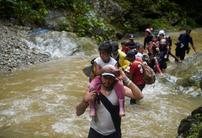 A migrant carries a child as they along with others continue their journey to the U.S. border, in Acandi, Colombia July 9, 2023. REUTERS/Adri Salido 