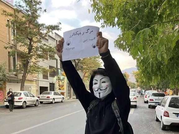 A protester in Tehran holding up a sign that says, "Death to the dictator". October 2022
