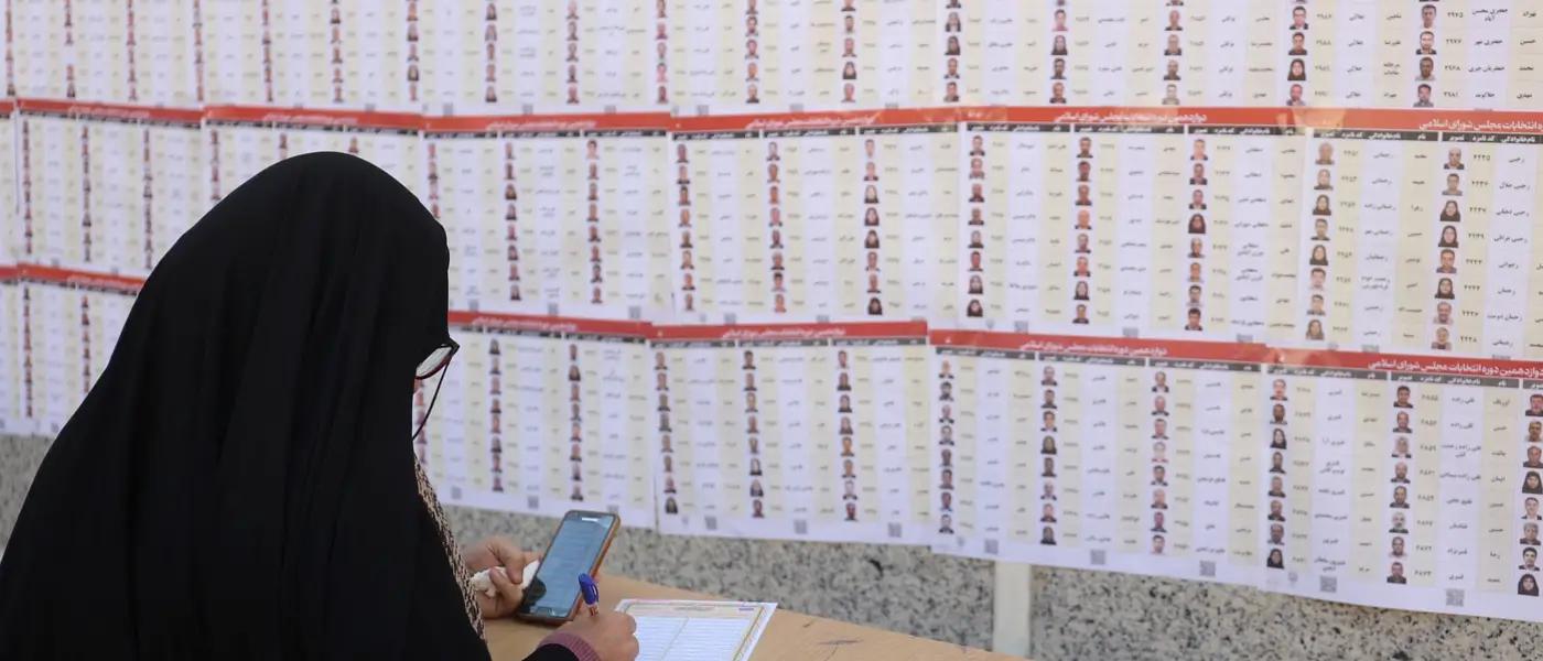 An Iranian woman checks the names of candidates during parliamentary elections at a polling station in Tehran, Iran, March 1, 2024.
