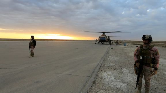 Iraqi security forces at Ain al-Asad airbase near a military helicopter in Anbar province, Iraq, December 29, 2019.