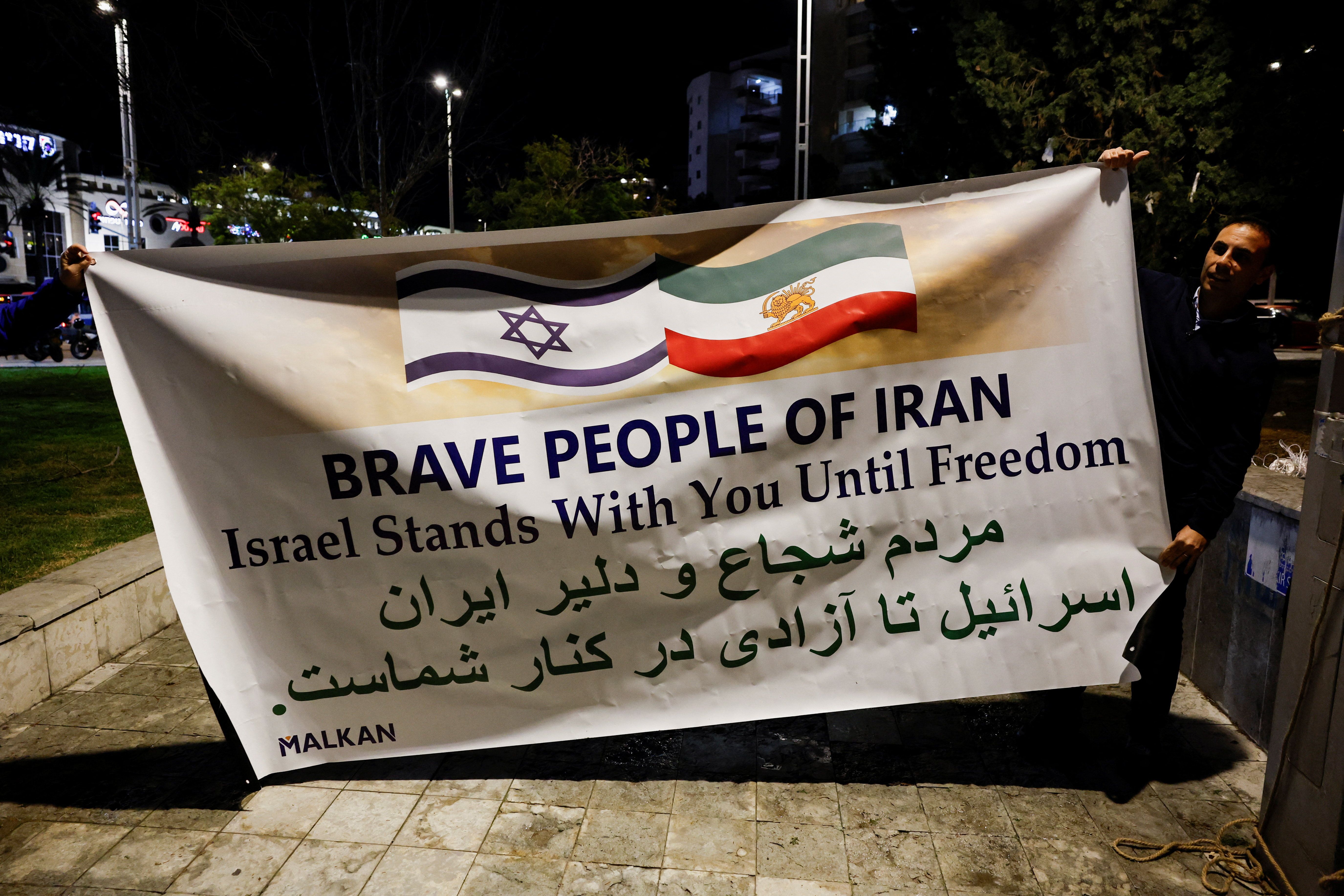 People hold a banner, as Israelis rally in support of the nationwide protests happening in Iran, in Holon, Israel, January 14, 2026. 