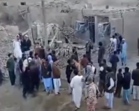 A group of people have gathered around the rubbles of buildings destroyed in Pakistan's airstrikes against Iran
