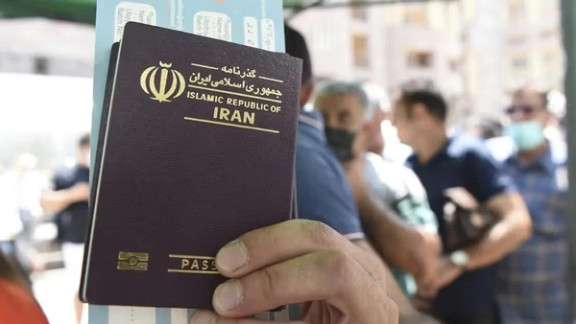 A person holds up an Iranian passport while standing in a queue at airport (Undated)