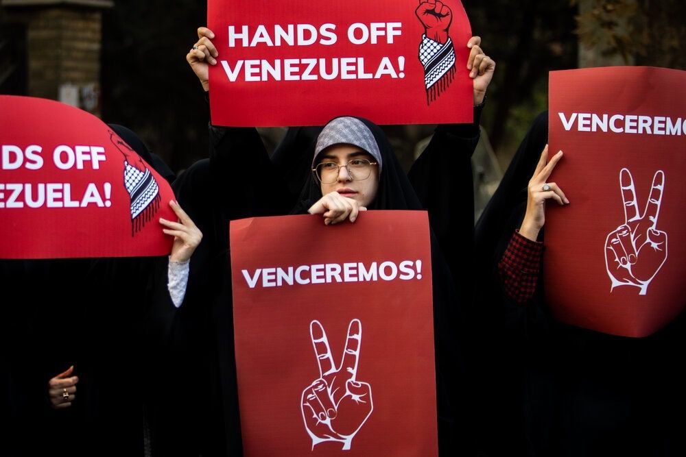 Protesters hold up posters in support of Venezuela, in front of the Swiss embassy in Tehran, which represents US interests in Iran, November 2025