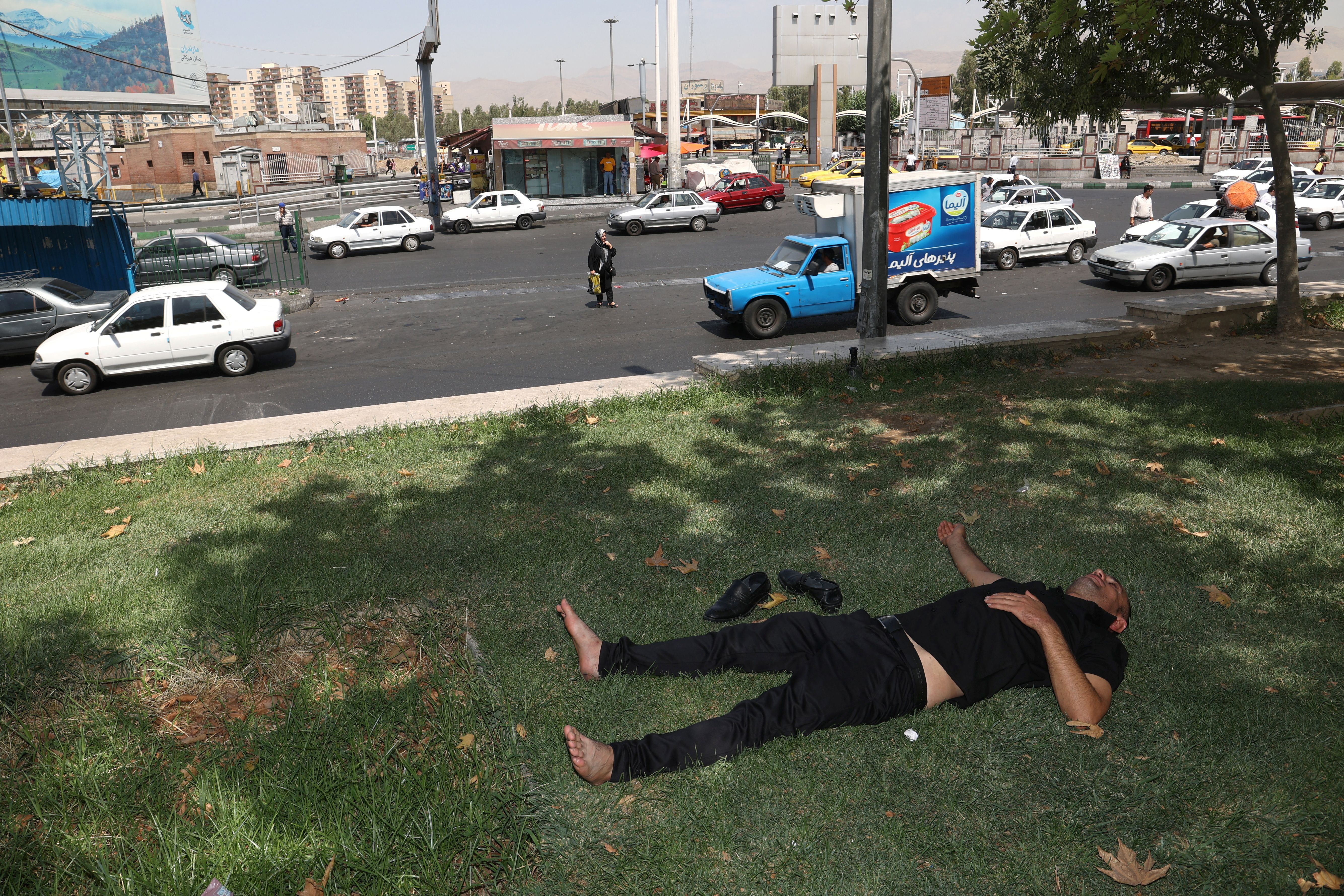 An Iranian man rests in the shade of a tree during the heat surge in Tehran, August 2, 2023.