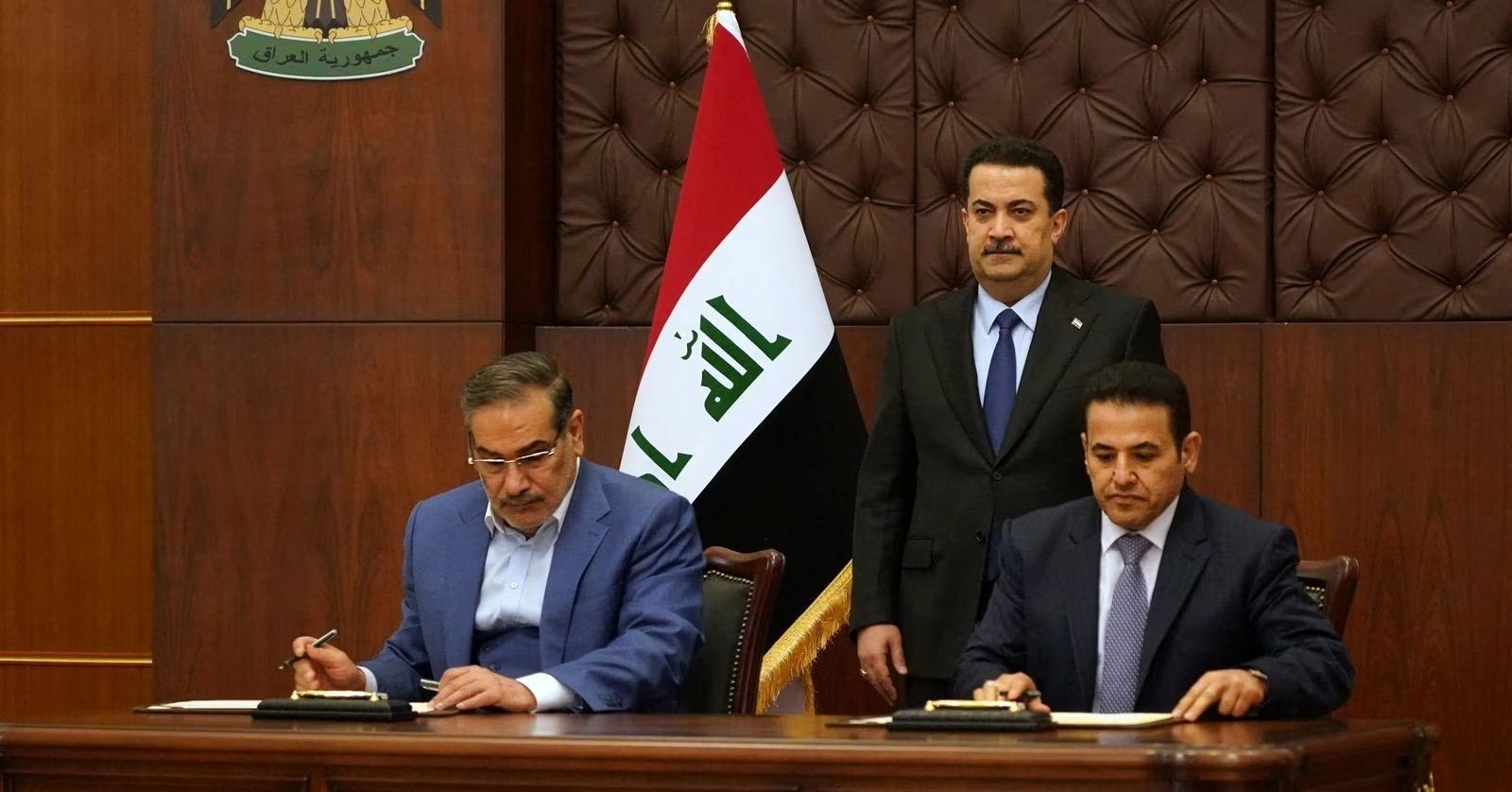 Iraqi Prime Minister Mohammed Shia al-Sudani looks on as Iraq's National Security Adviser Qasim al-Araji and Iran's former Supreme National Security Council secretary Ali Shamkhani sign a security agreement in Baghdad, March 19, 2023.
