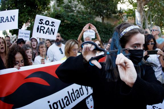 A woman cuts her hair during a protest against the Islamic regime of Iran and the death of Mahsa Amini in front of the Iranian Embassy in Madrid, October 6, 2022