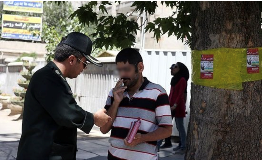 Police stopping a man on the street for smoking during the month of Ramadhan. Undated