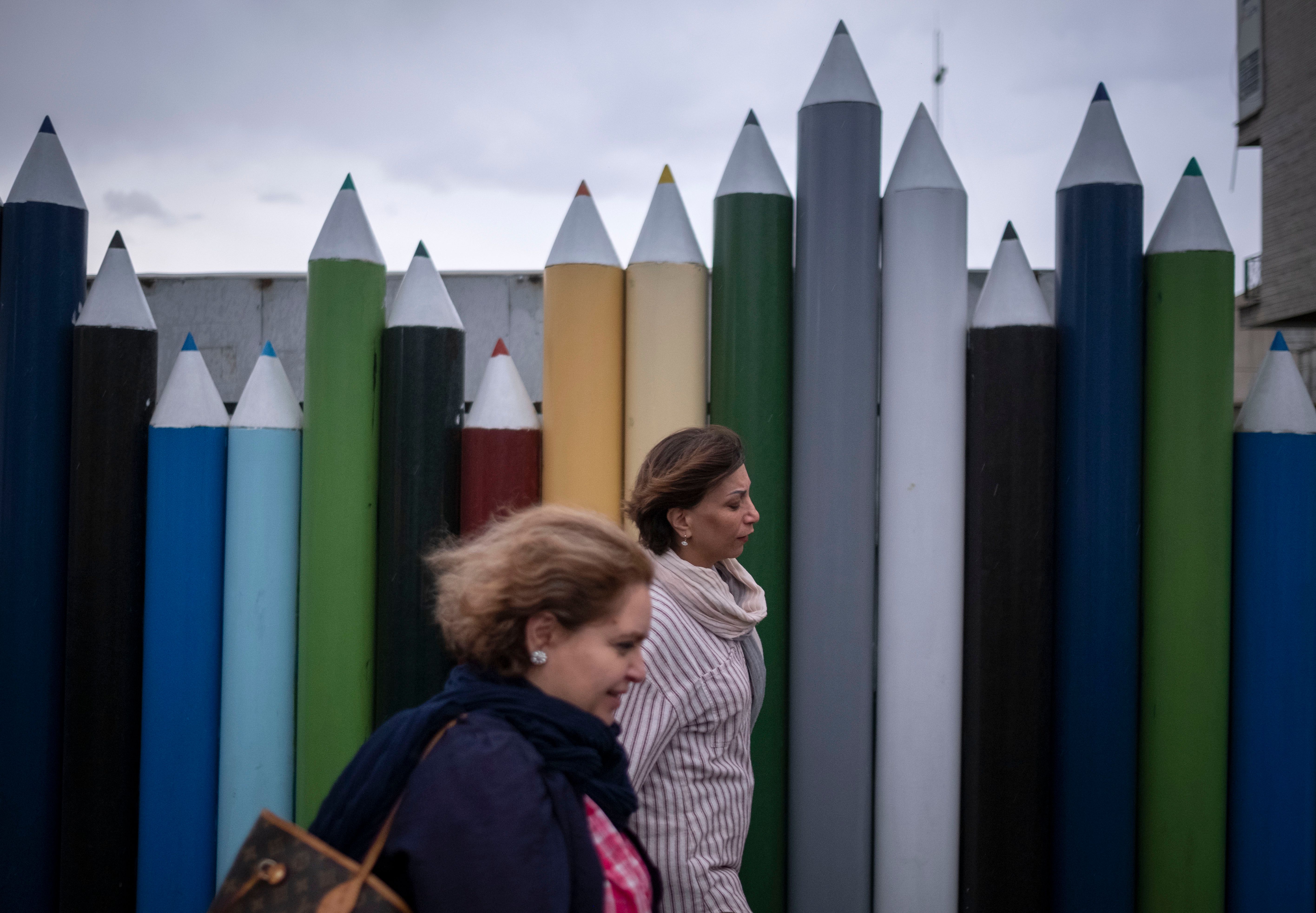 Two Iranian women walk past an urban art without wearing the mandatory Islamic headscarf in downtown Tehran,on June 8, 2023.