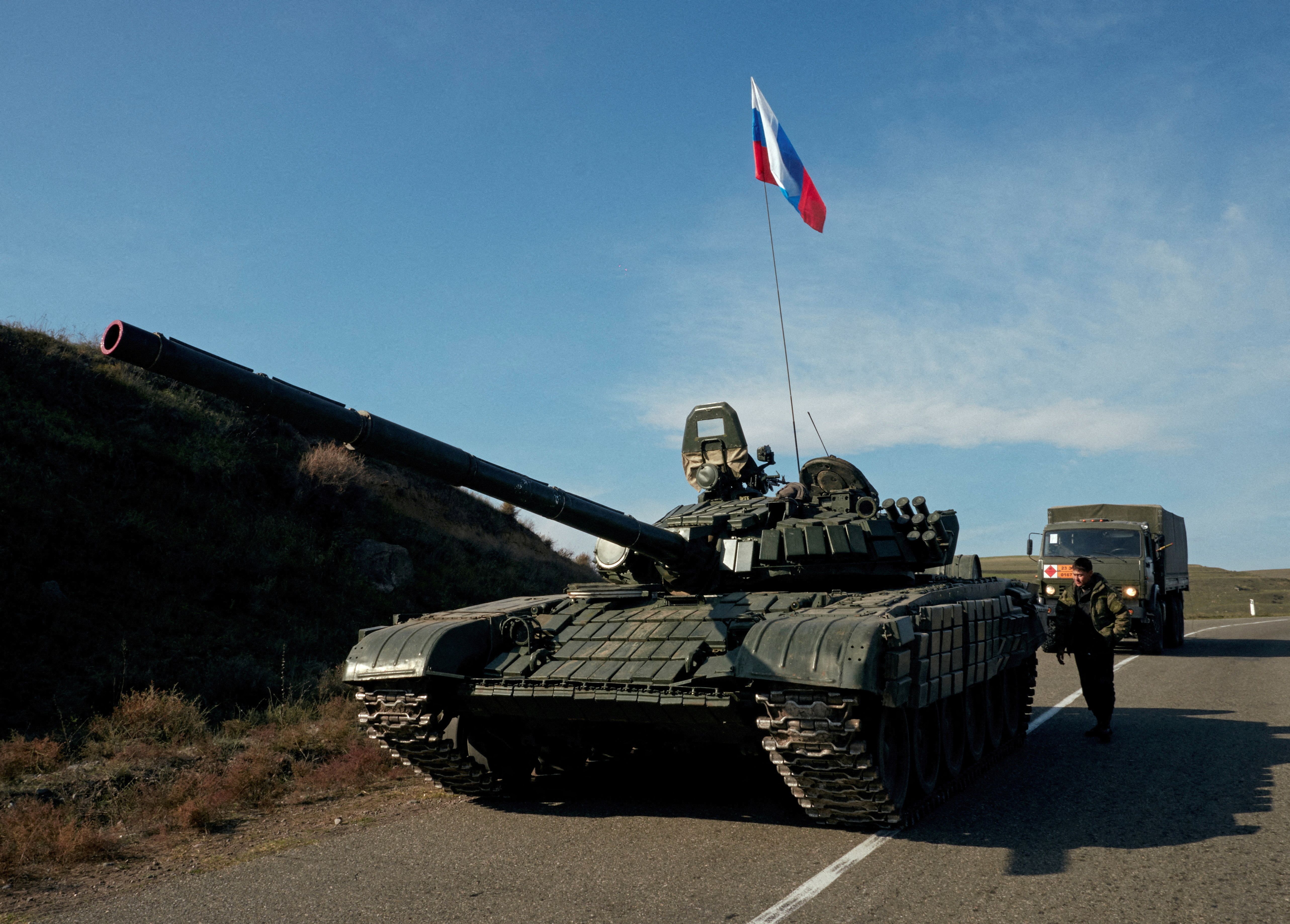 A service member of the Russian peacekeeping troops stands next to a tank near the border with Armenia, following the signing of a deal to end the military conflict between Azerbaijan and ethnic Armenian forces, in the region of Nagorno-Karabakh, November 10, 2020.