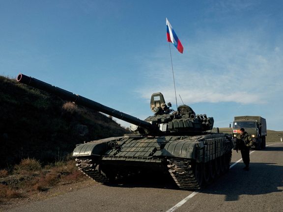 A service member of the Russian peacekeeping troops stands next to a tank near the border with Armenia, following the signing of a deal to end the military conflict between Azerbaijan and ethnic Armenian forces, in the region of Nagorno-Karabakh, November 10, 2020.
