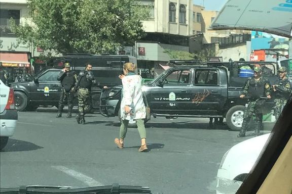 A woman without the mandatory hijab passing in front of security measures in Tehran on the eve of rallies for the anniversary of Mahsa Amini (September 2023)