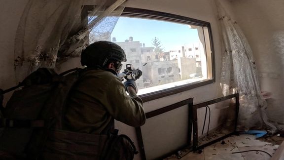 An Israeli soldier fires a weapon from a window during operations in the Gaza Strip (December 2023)