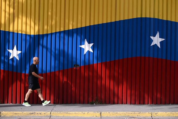 A man walks past a mural with the colors of the Venezuelan flag, after US President Donald Trump said that the airspace above and around Venezuela would be completely closed, amid rising tensions between the Trump administration and the government of Venezuelan President Nicolas Maduro, in Caracas, Venezuela, November 29, 2025.