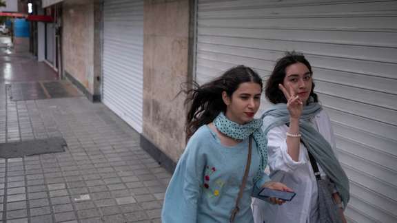 Two Iranian women walk along a street-side without wearing the mandatory Islamic headscarf in downtown Tehran,on June 8, 2023.
