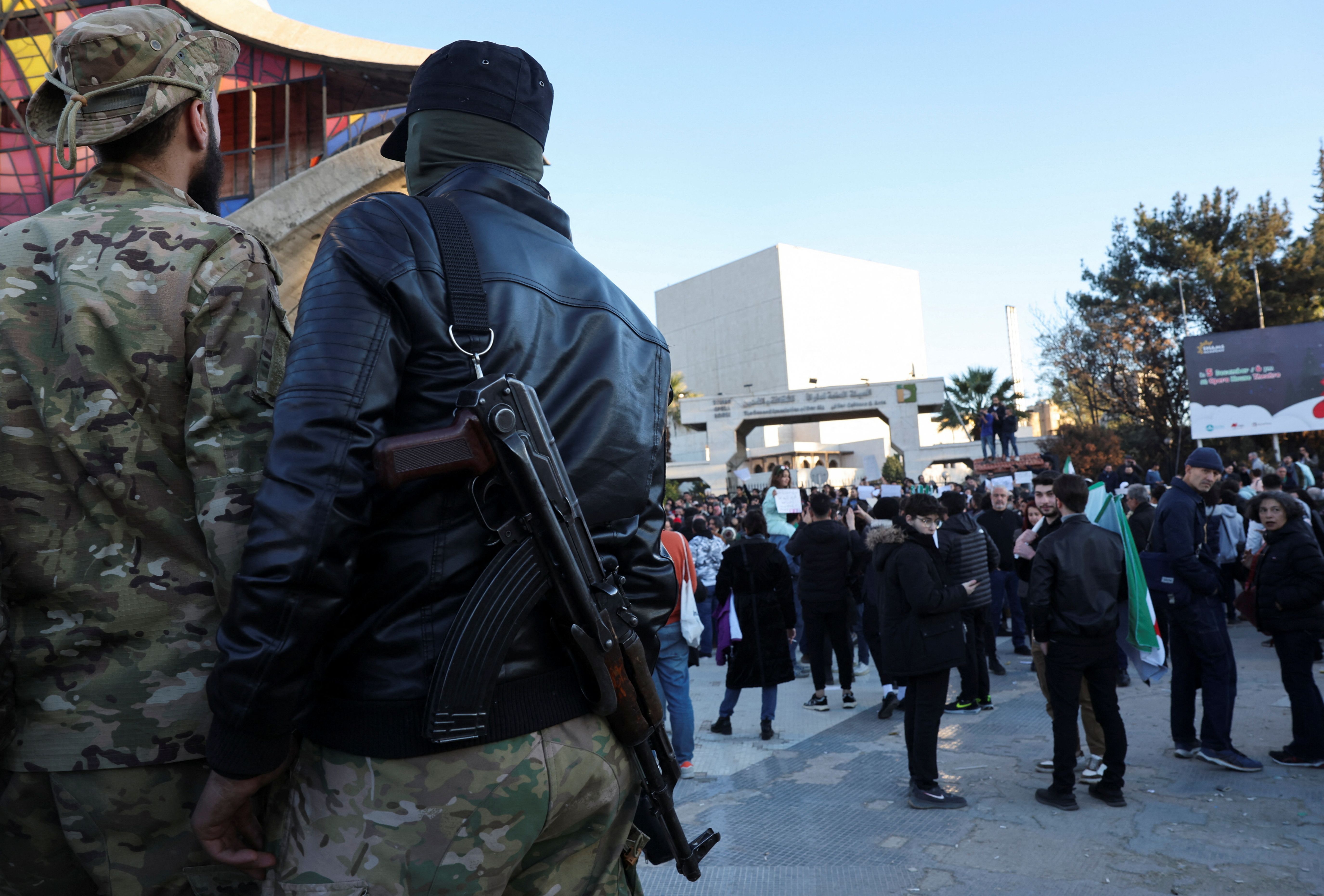 اعضای گروه‌های مسلح حاکم بر دمشق در حال تماشای تظاهرات در میدان اموی این شهر، ۲۹ آذر