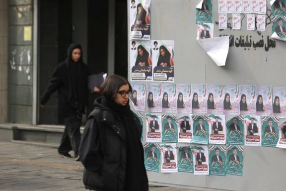 A young Iranian woman is walking past electoral posters in downtown Tehran, February 2024.