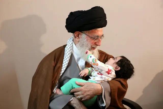 Iran's Supreme Leader Ali Khamenei holding a baby