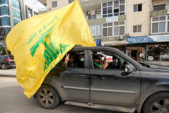 A man gestures the victory sign as he holds a Hezbollah flag, on the second day of the ceasefire between Israel and Iran-backed group Hezbollah, in Tyre, southern Lebanon November 28, 2024