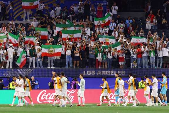 Iran players walk past Iranian fans holding official and pre-revolutionary flags, in Los Angeles, US, June 16, 2026