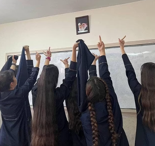 Iranian schoolgirls raising their middle fingers at a portrait of Iran's leaders in a classroom. 