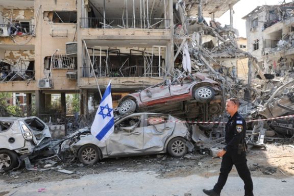 An Israeli police officer walks past damaged vehicles at an impact site following missile attack from Iran on Israel, in Ramat Gan, Israel, June 14, 2025.